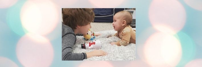 Boy and baby with toys laying on tummy in the floor