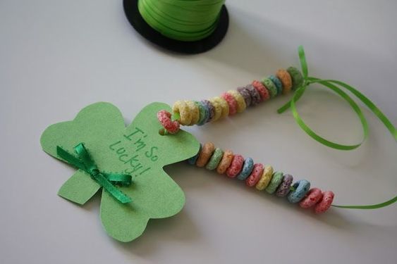 Homemade necklace with rainbow colored cereal on a string with a shamrock cut out of construction paper. The shamrock says "I'm so lucky".