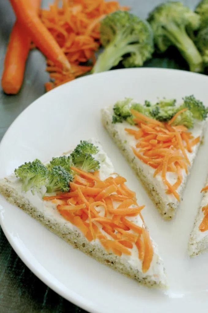 Veggie pizza made to look like carrots for Easter, by using chopped broccoli along the top edge and shredded carrots covering the rest.